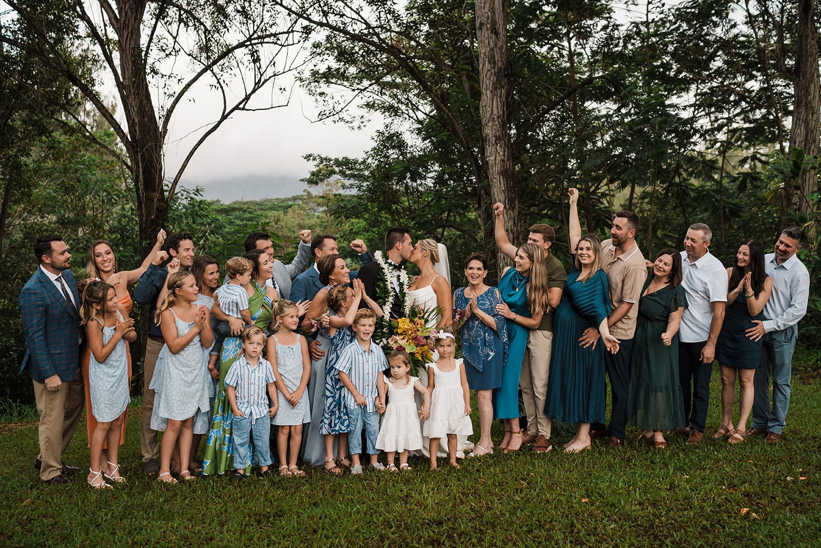 Guests cheer while bride and groom kiss during their Kauai wedding weekend.