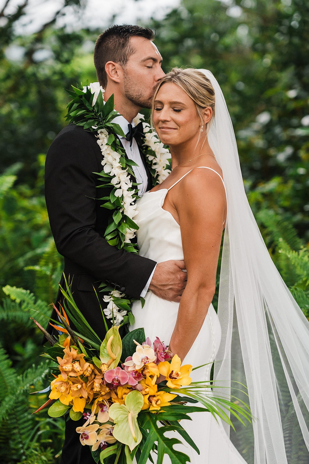 Groom kisses bride on her hair during their Kauai wedding portraits.