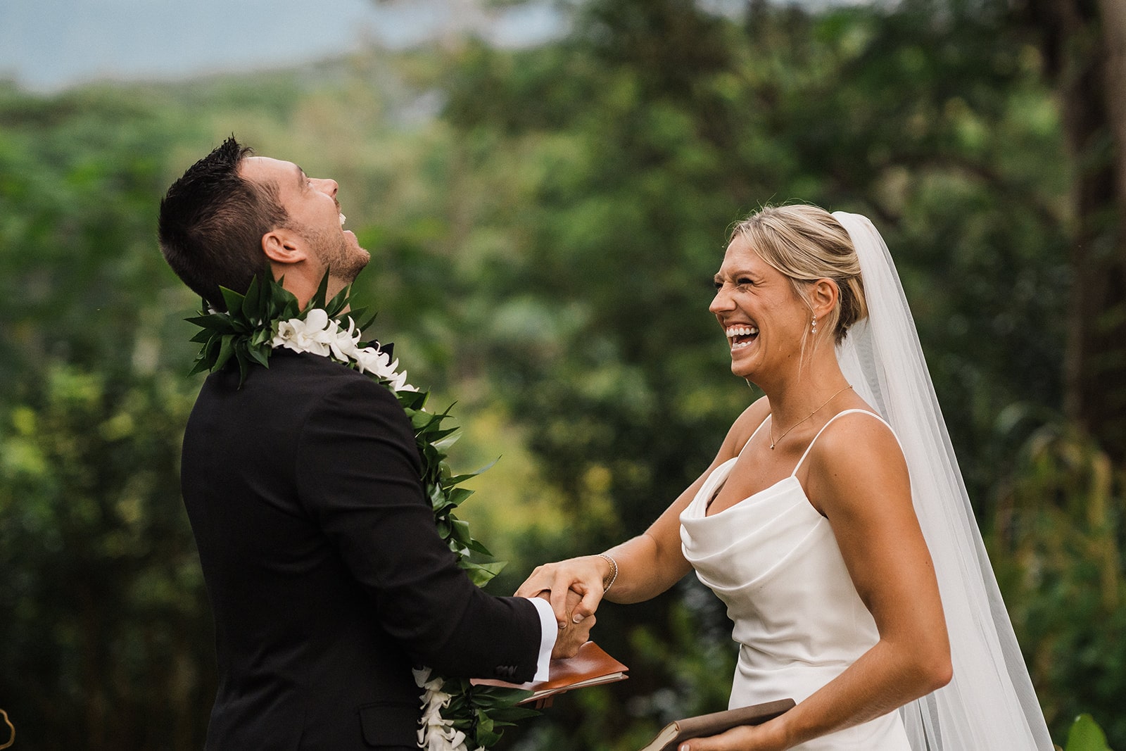 Bride and groom laugh while playing rock, paper, scissors at their Kauai wedding.