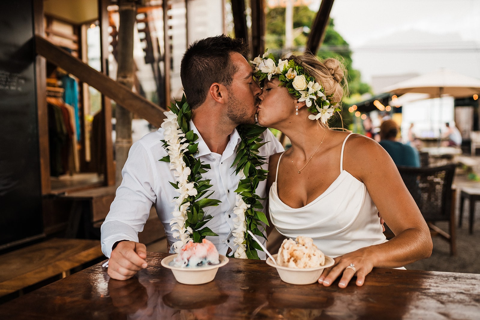 Bride and groom kiss while eating shave ice at their three-day Kauai wedding.