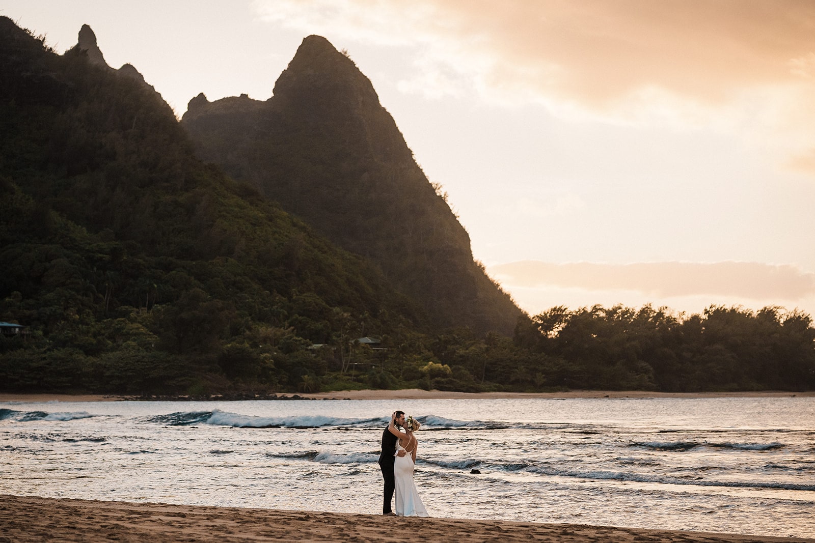 Bride and groom kiss on the beach at sunset during their Kauai micro wedding.