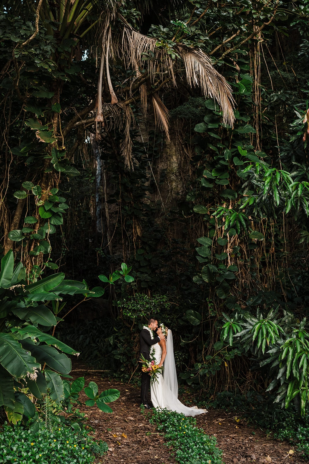 Bride and groom kiss in the rainforest while eloping in Kauai.
