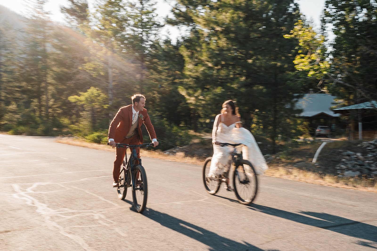 Bride and groom ride bikes in their wedding attire during their intimate wedding in the North Cascades.