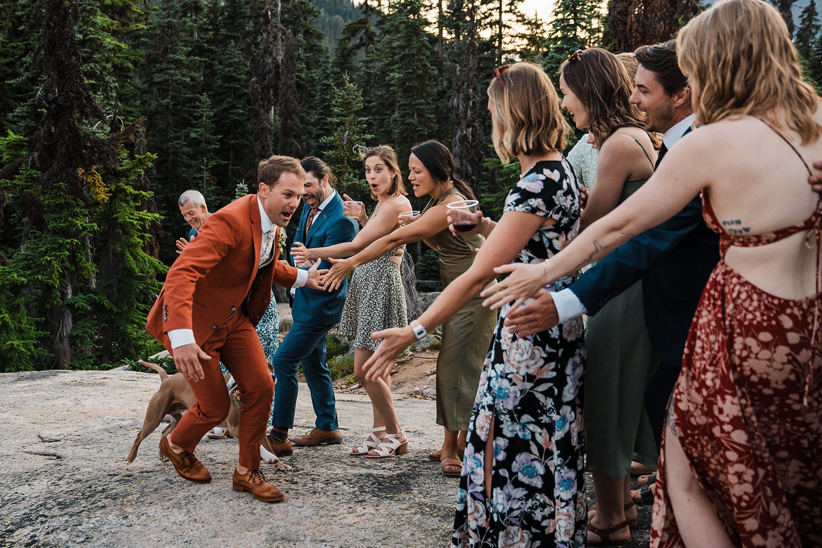 Groom runs by guests and high fives after their wedding weekend ceremony in the mountains.