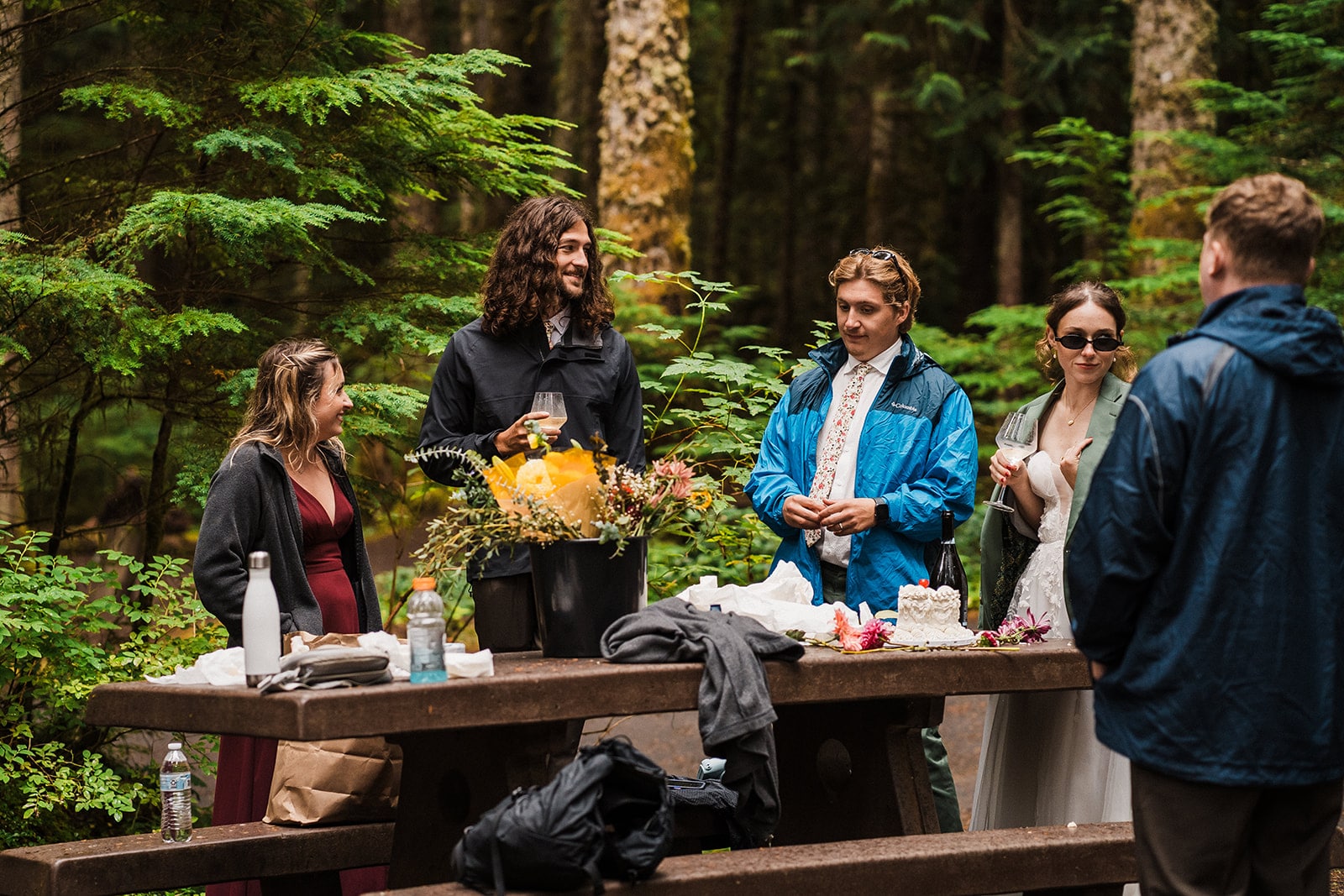 Guests mingle around a campsite table at an outdoor multi-day wedding.