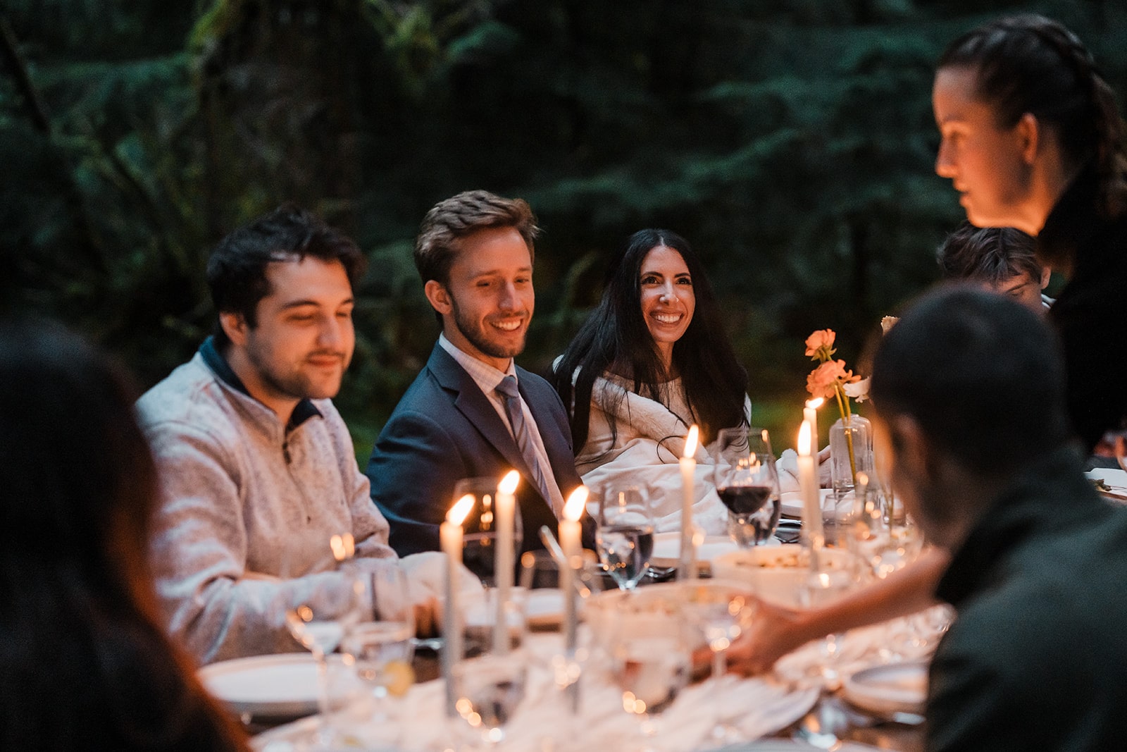 Guests enjoy a candlelit dinner in the forest at a multi-day Washington wedding.