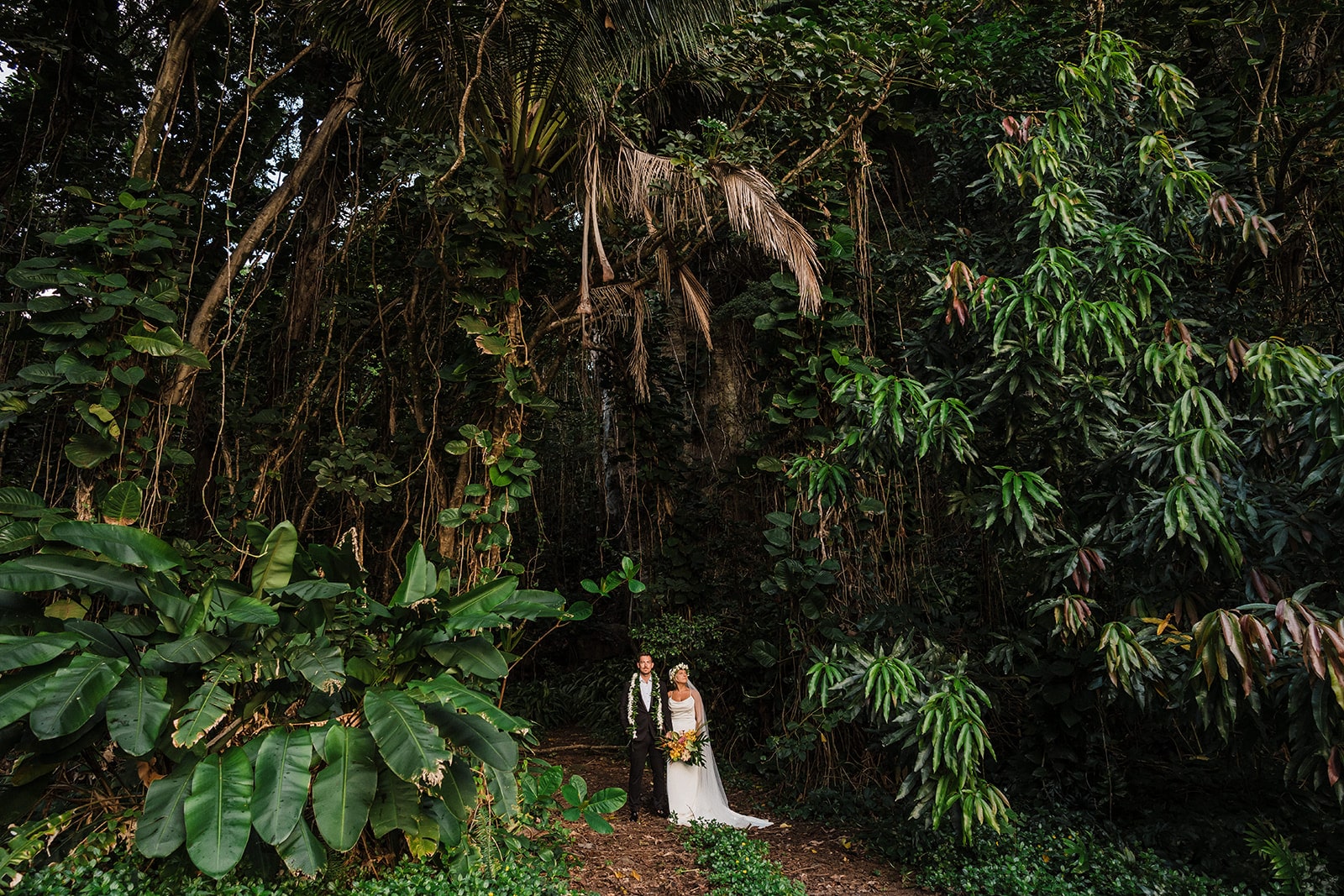 Bride and groom stand at the edge of a jungle during their Kauai elopement.