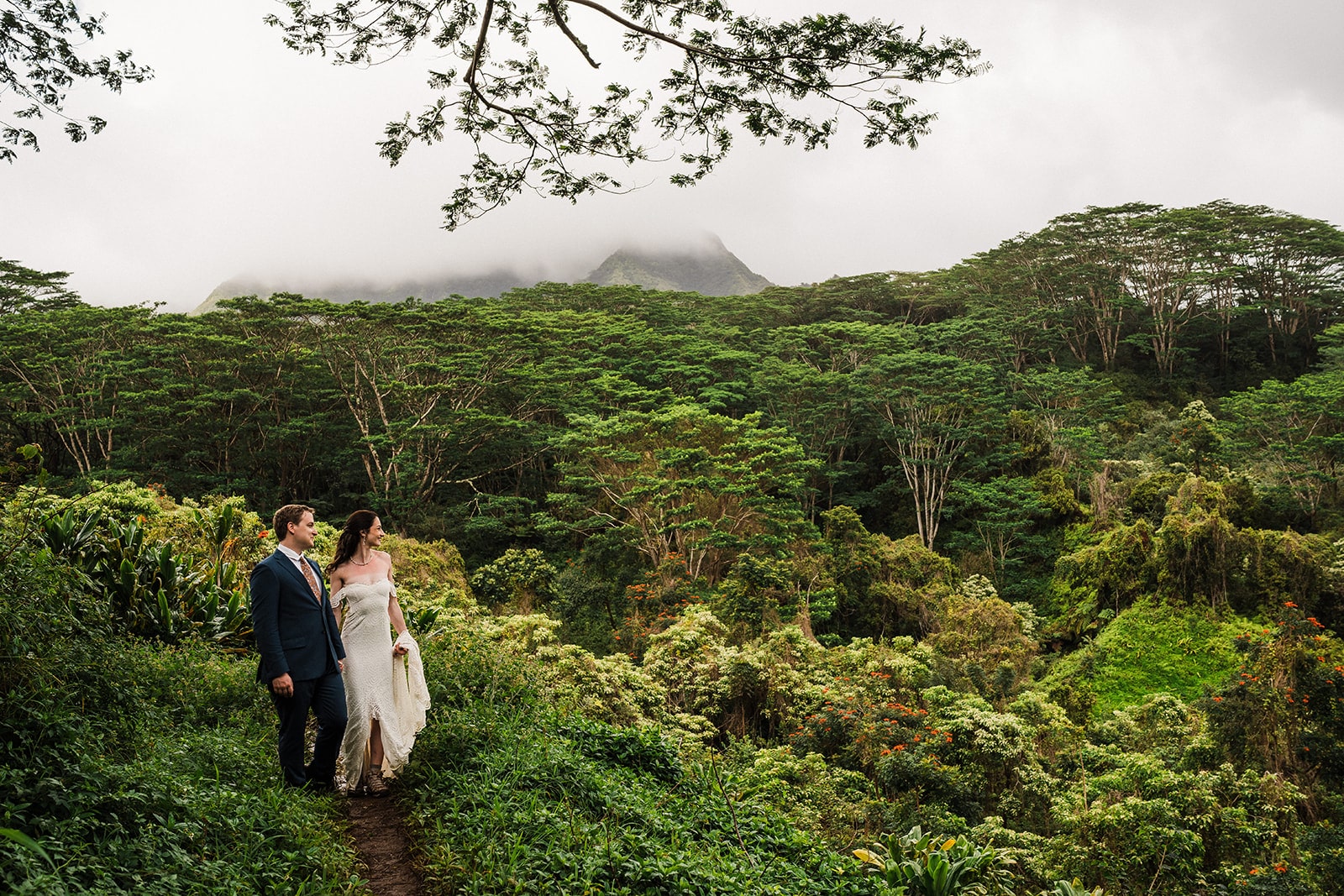 Bride and groom hold hands on a ridge trail near Kauai's South Shore.