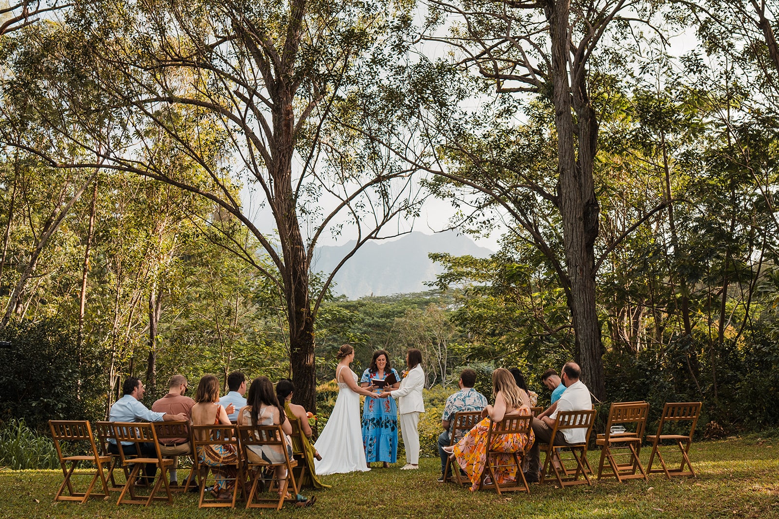 Brides hold hands during their wedding ceremony at Common Ground, one of the best Kauai elopement locations.