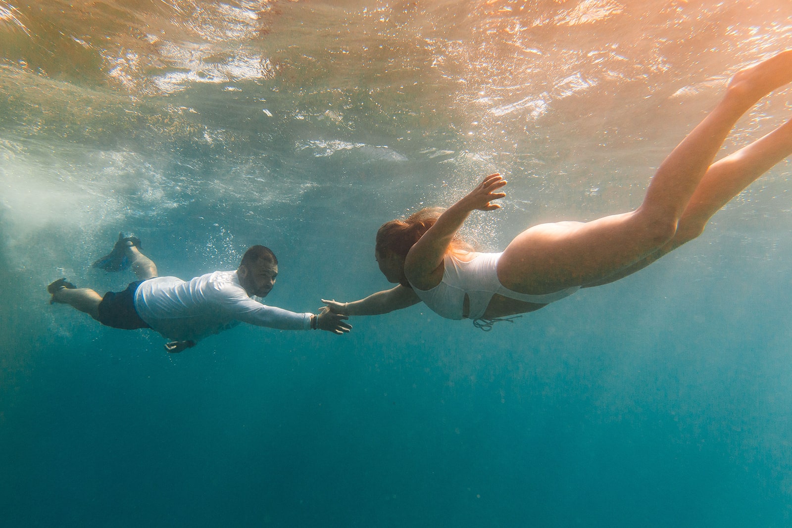 Man and woman reach for each other's hands while snorkeling in Kauai - one of the top things to do on Kauai.