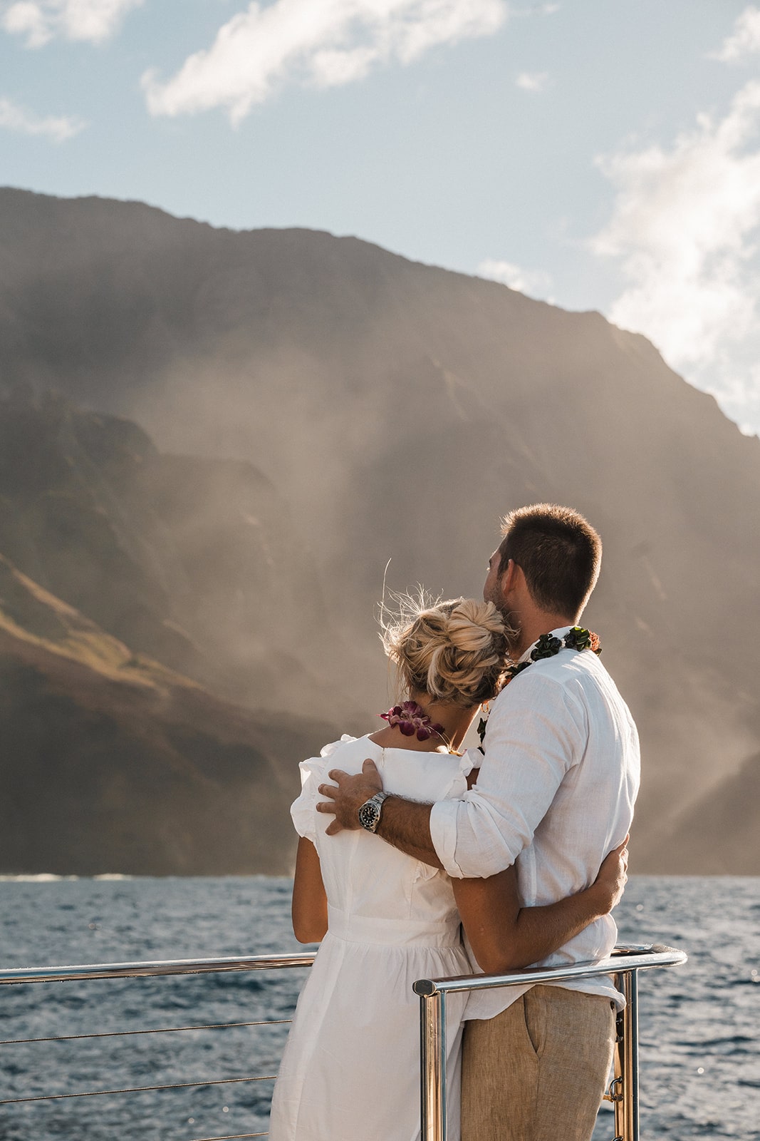 Bride and groom stand on a chartered boat watching the Napali Coastline during their Kauai Hawaii activities and elopement. 