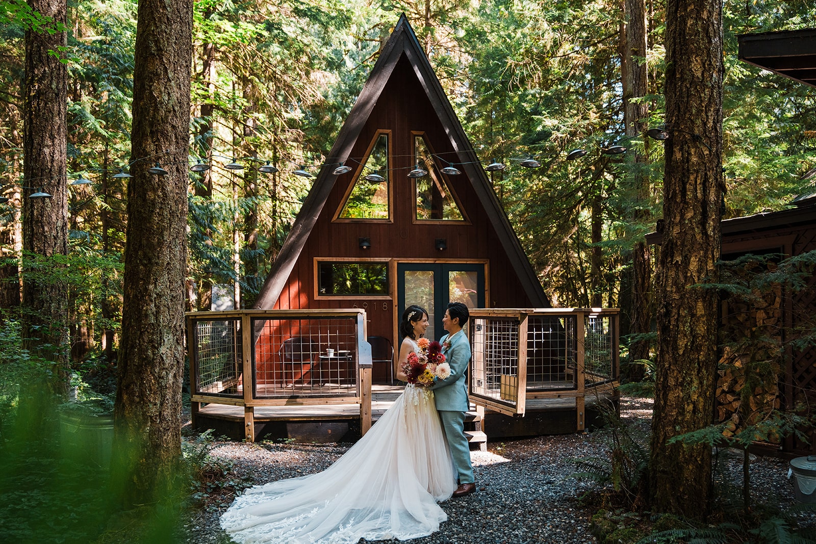 Brides hug in front of an A-frame forest cabin in Washington during their elopement.