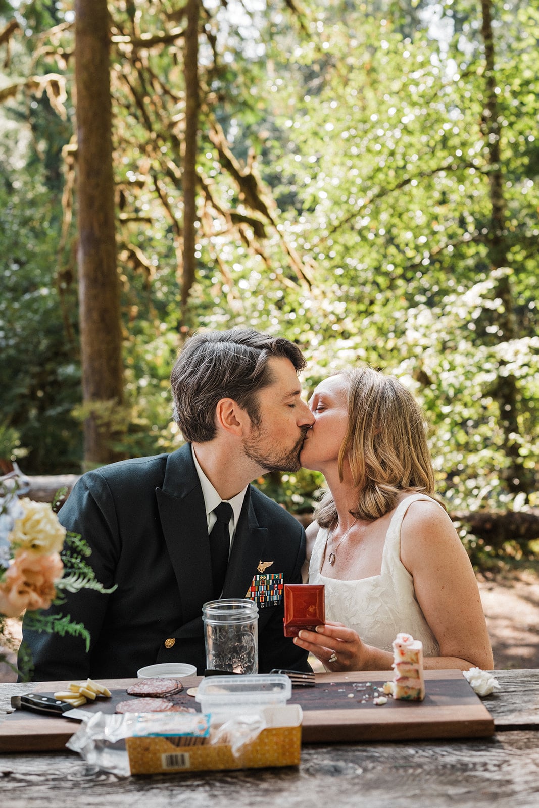 Bride and groom kiss while sitting at a picnic table during their elopement. 