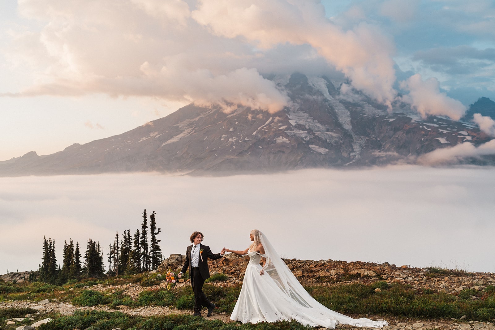 Man and woman hold hands in front of a mountain during their adventure elopement.
