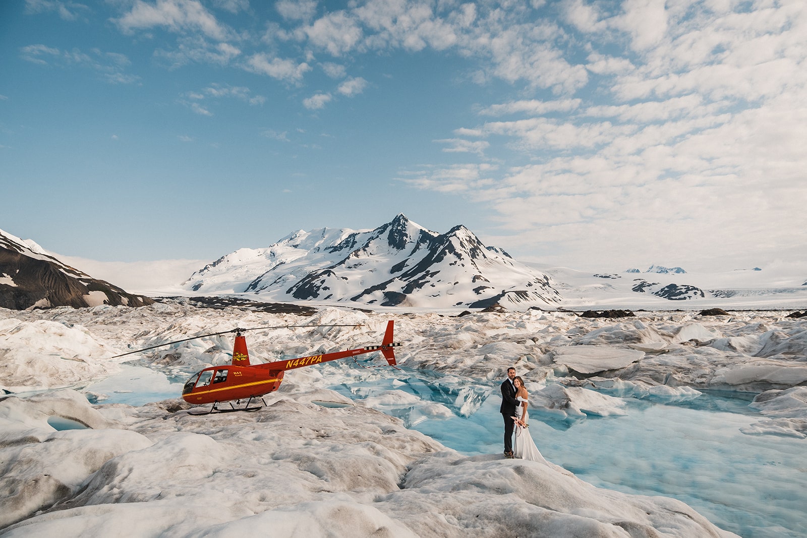 Bride and groom stand on an icy glacier during their Alaska helicopter elopement. 