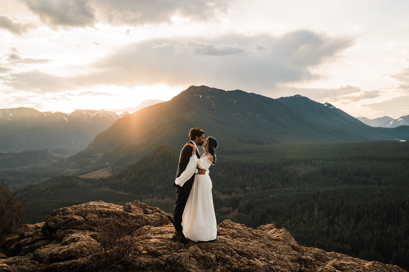 Bride and groom kiss on a mountain trail in Snoqualmie at sunrise during their unique PNW elopement. 
