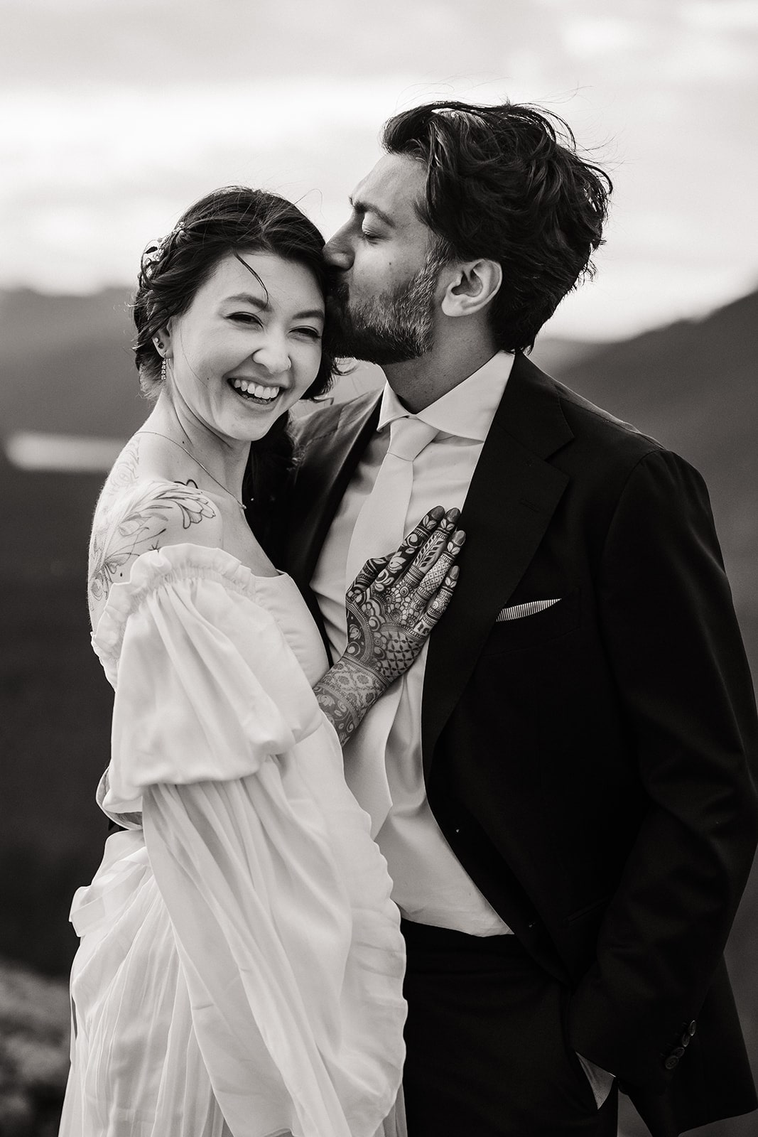 Groom kisses bride on her hair during their sunrise mountain elopement photos in Snoqualmie, Washington. 
