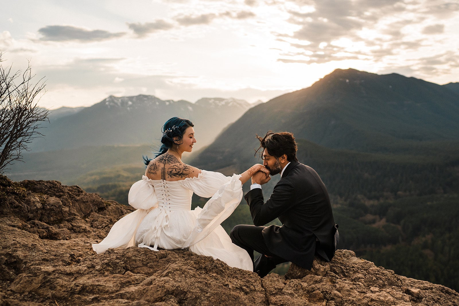 Bride and groom sit on a mountain trail during sunrise during their unique elopement in Washington. 