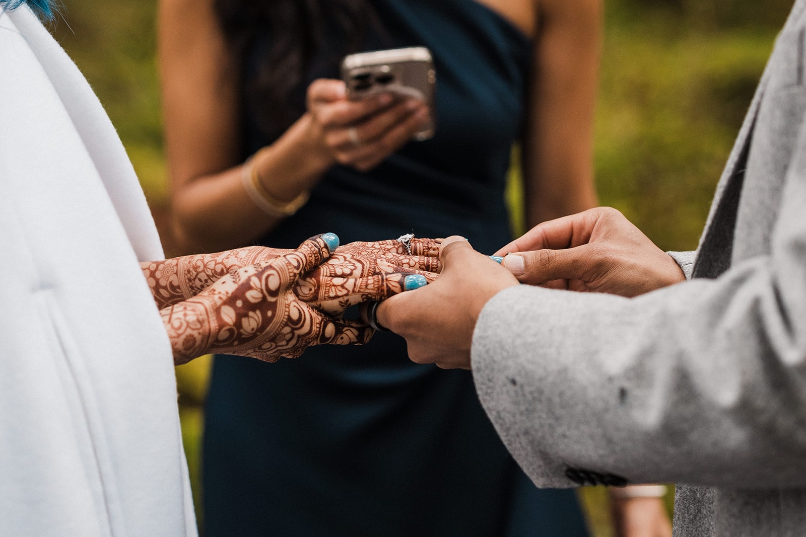 Groom puts a ring on bride's hand with henna. 