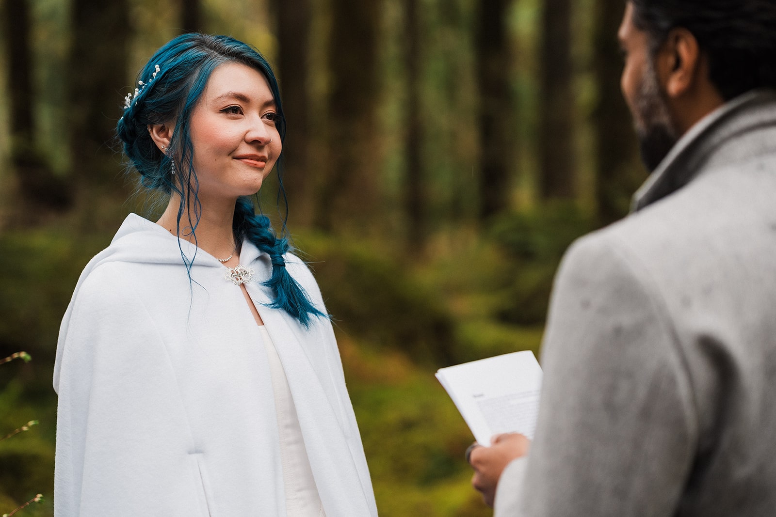 Bride smiles emotionally wile groom reads vows during their unique elopement ceremony in the forest in Snoqualmie. 