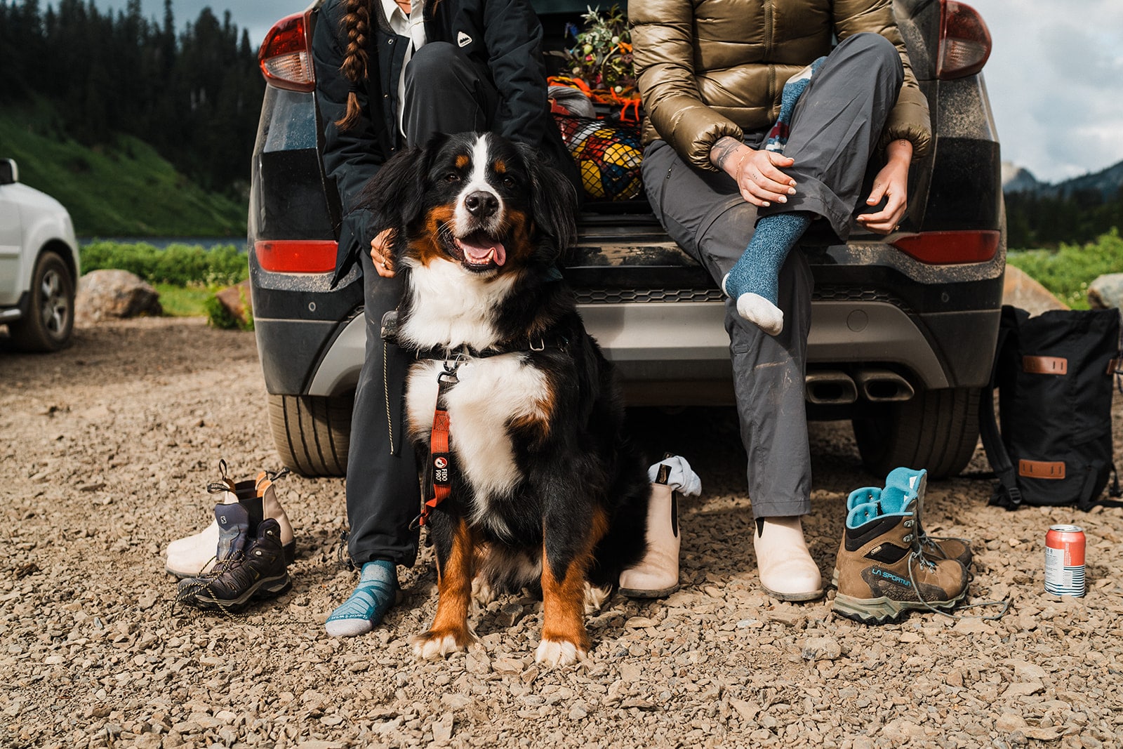 Dog sits while two women put on their hiking boots for their adventure elopement hike.