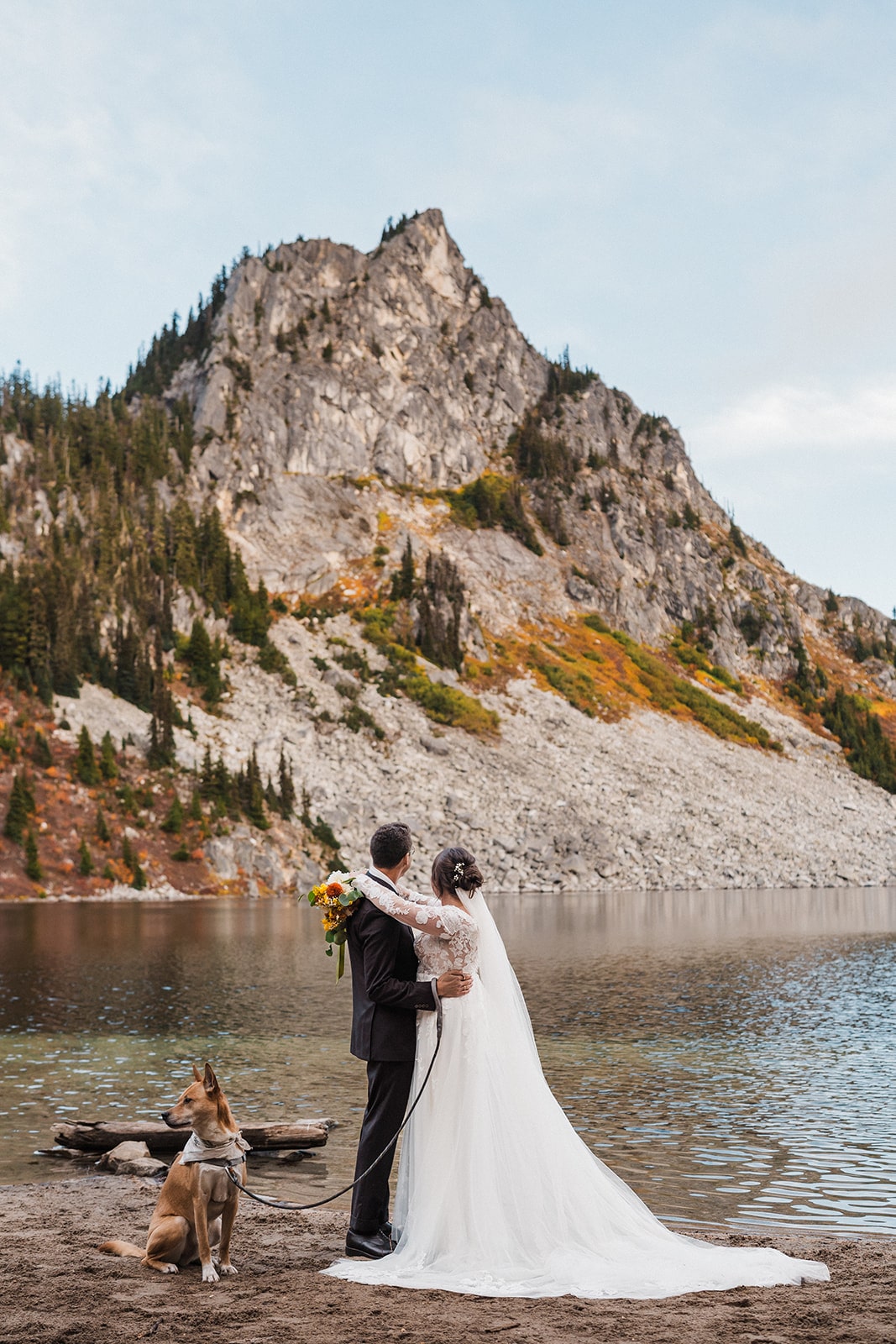 Bride and groom hug next to an alpine lake in Lake Wenatchee State Park.
