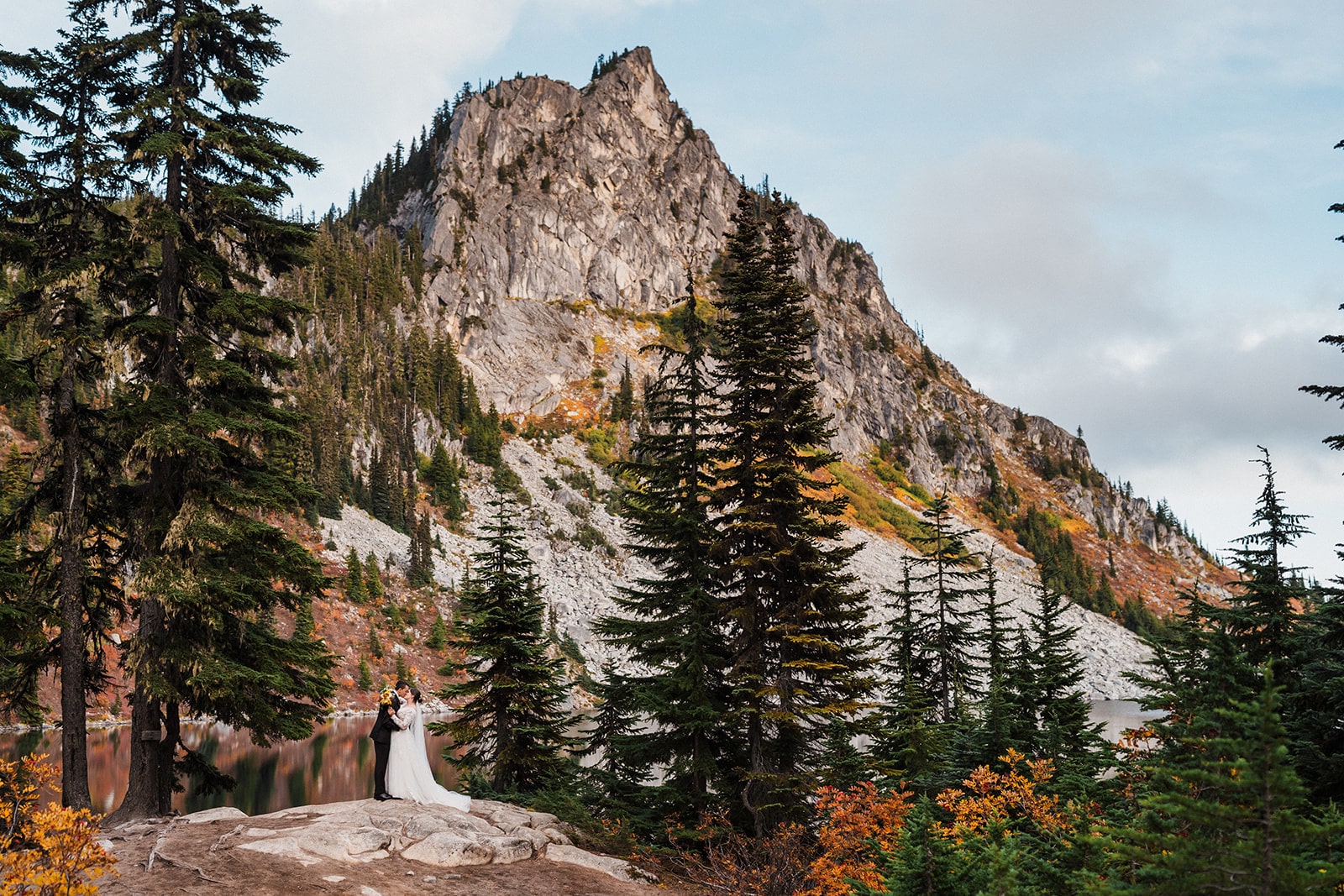 Bride and groom stand in front of a mountain at their Lake Wenatchee State Park wedding venue.