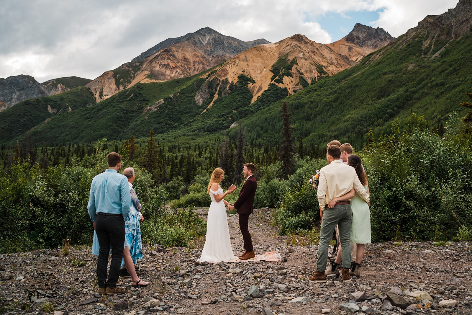 Bride reads vows to groom during their elopement in Alaska with guests. 