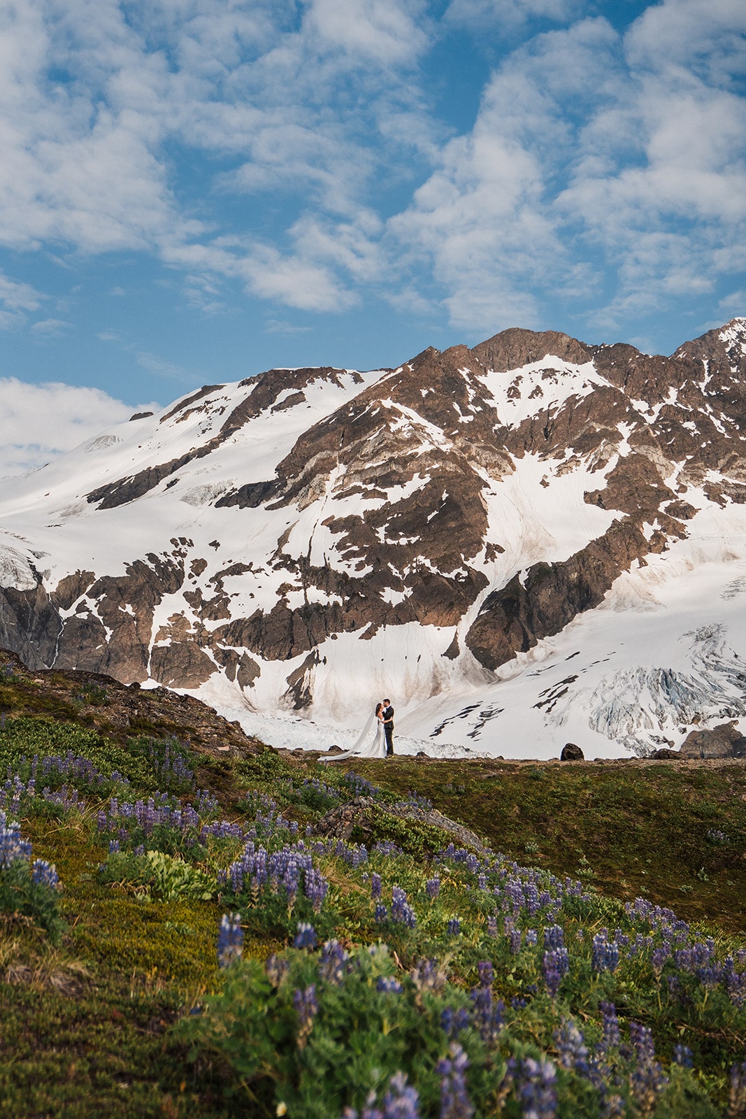 Bride and groom kiss on a mountain trail while they elope in Alaska. 