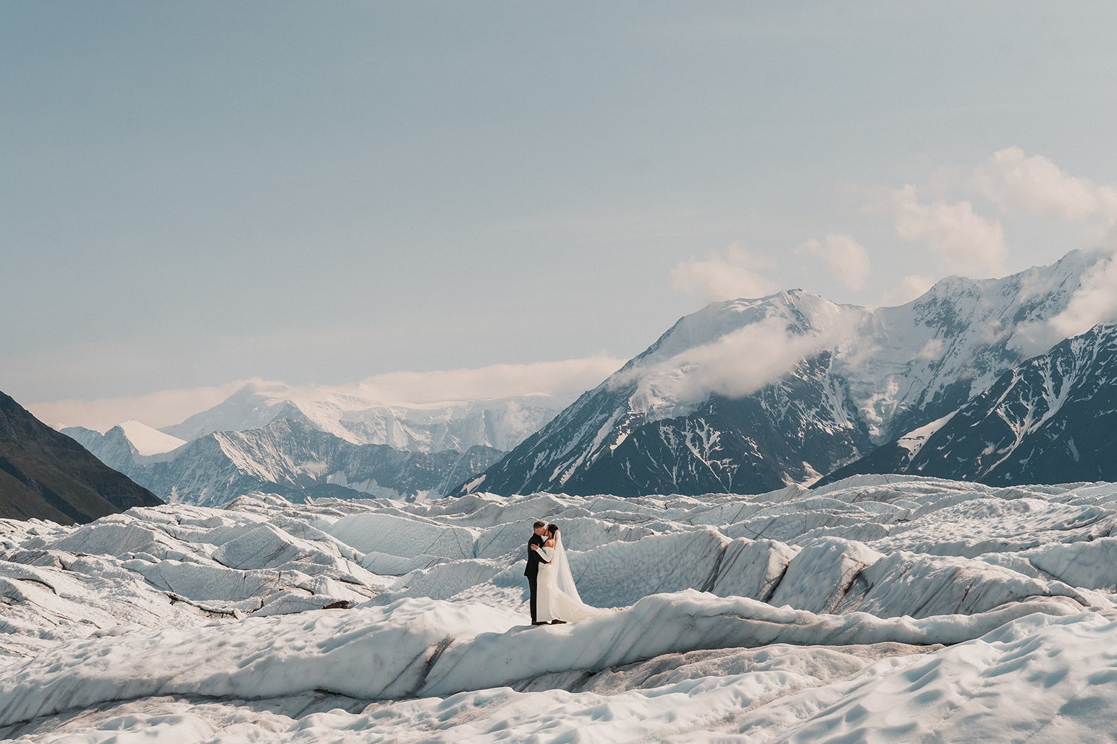 Bride and groom kiss in the snowy mountains while they elope in Alaska. 