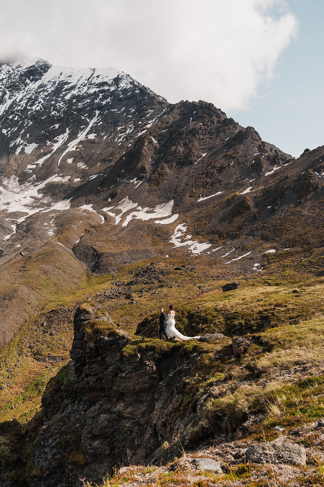 Bride and groom stand on a mountain trail during their elopement in Alaska. 