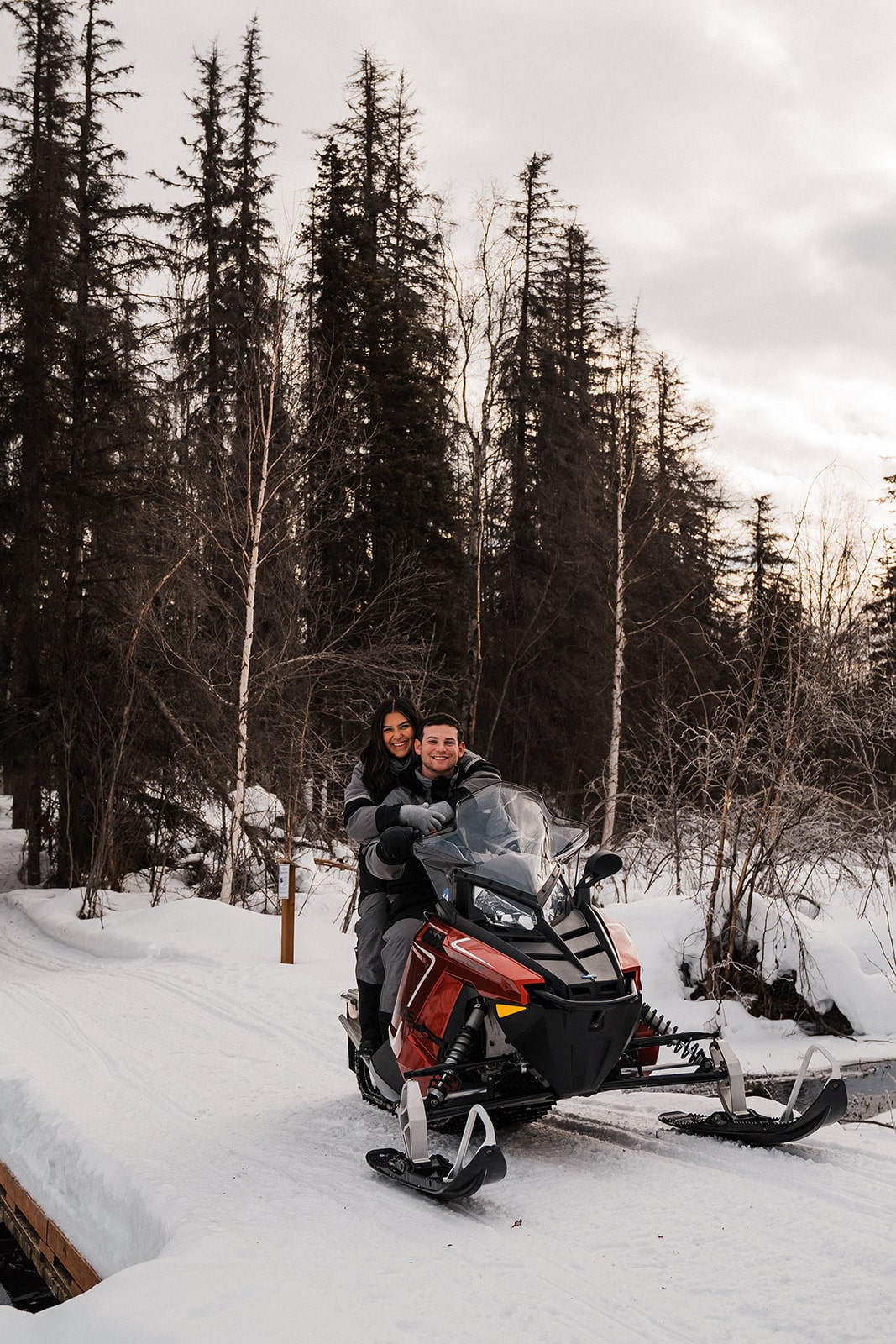 Bride and groom ride a snowmobile during their Alaska adventure elopement. 