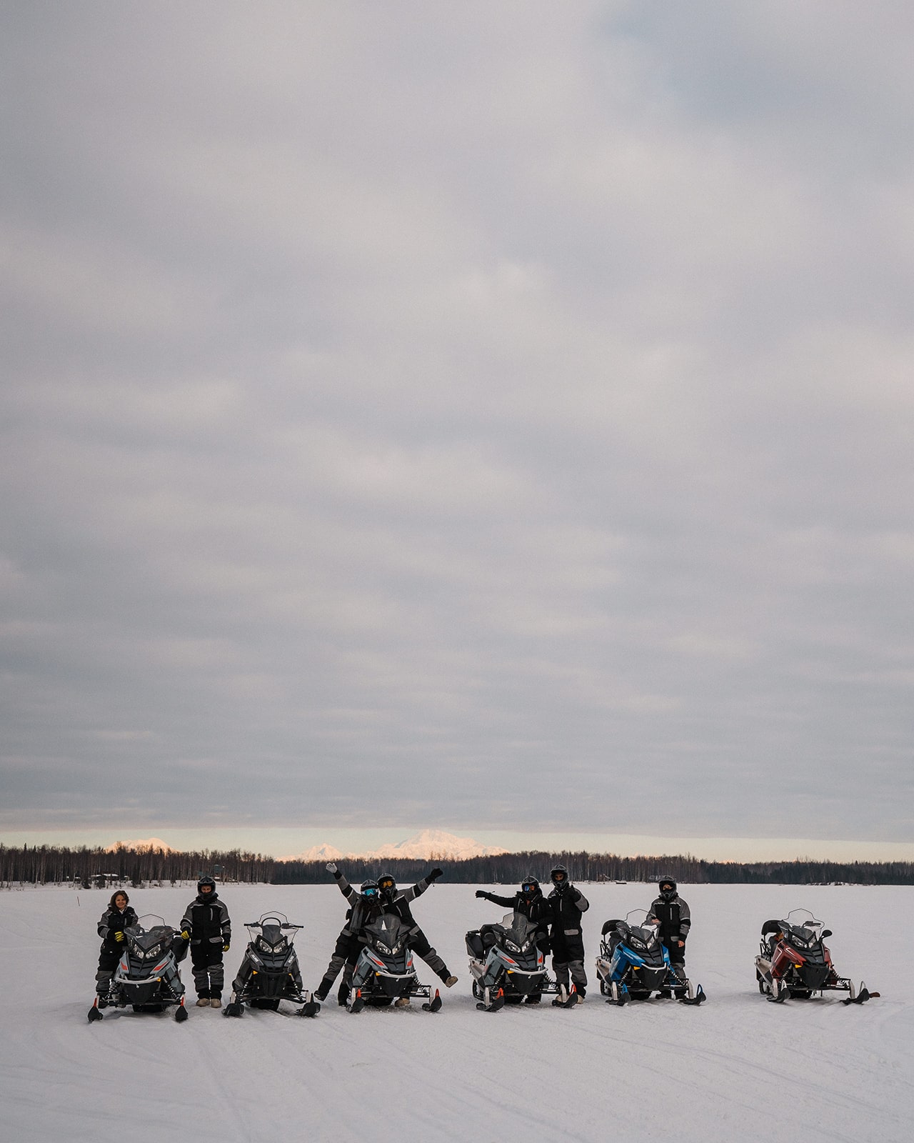 Bride and groom ride snowmobiles with their guests while they elope in Alaska. 