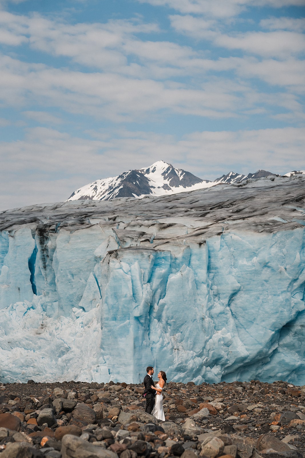 Bride and groom stand on a rocky glacier in Palmer, Alaska during their elopement adventure with Outbound Heli.