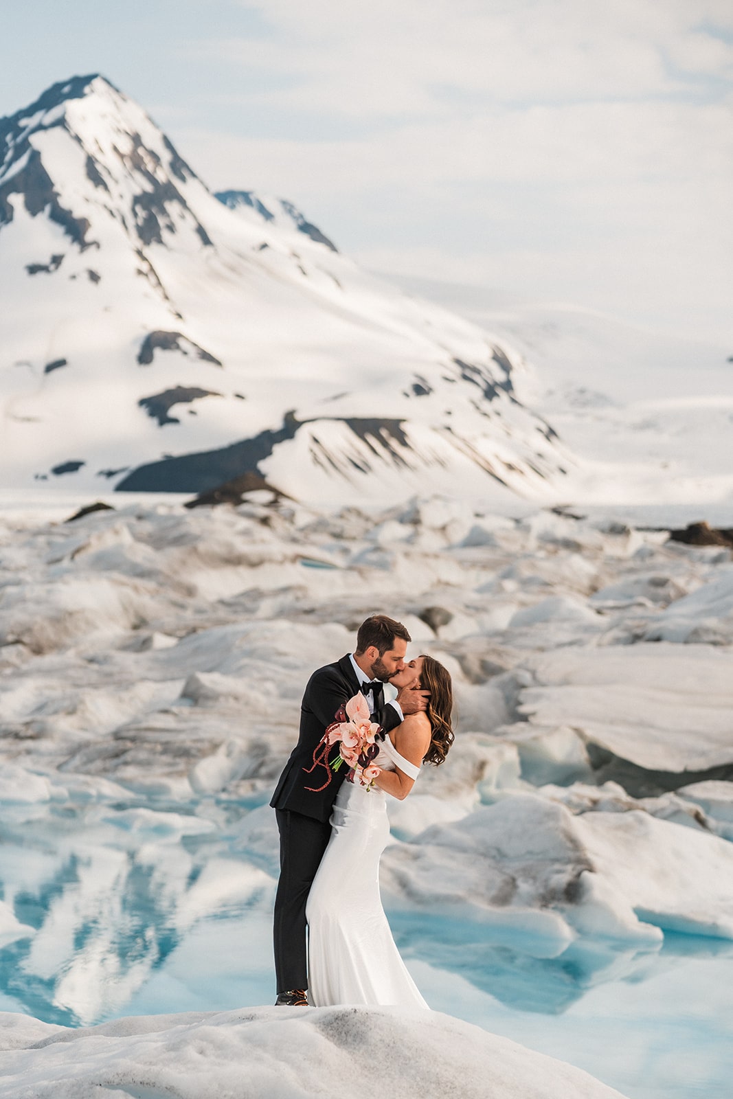 Bride and groom kiss on a snowy glacier during their Palmer, Alaska elopement.