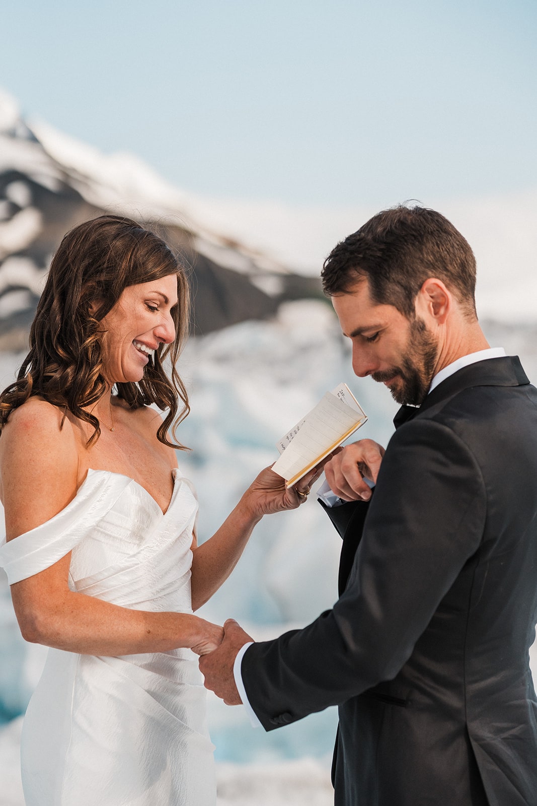 Bride gets emotional while reading personal vows to groom during their snowy summer glacier elopement in Alaska.