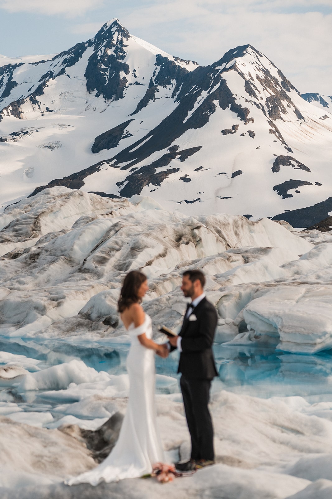 Bride and groom hold hands while reading vows during their Alaska glacier elopement ceremony.
