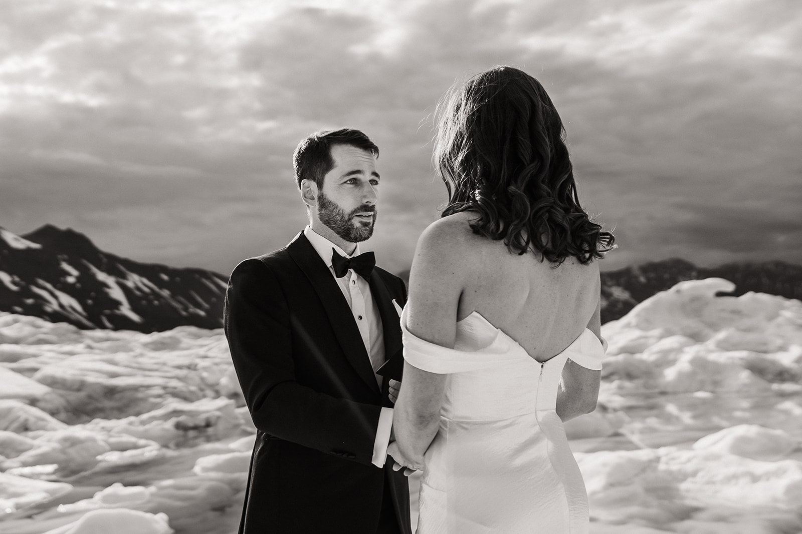 Groom reads personal vows to bride on a glacier during their multi-adventure elopement with Outbound Heli.