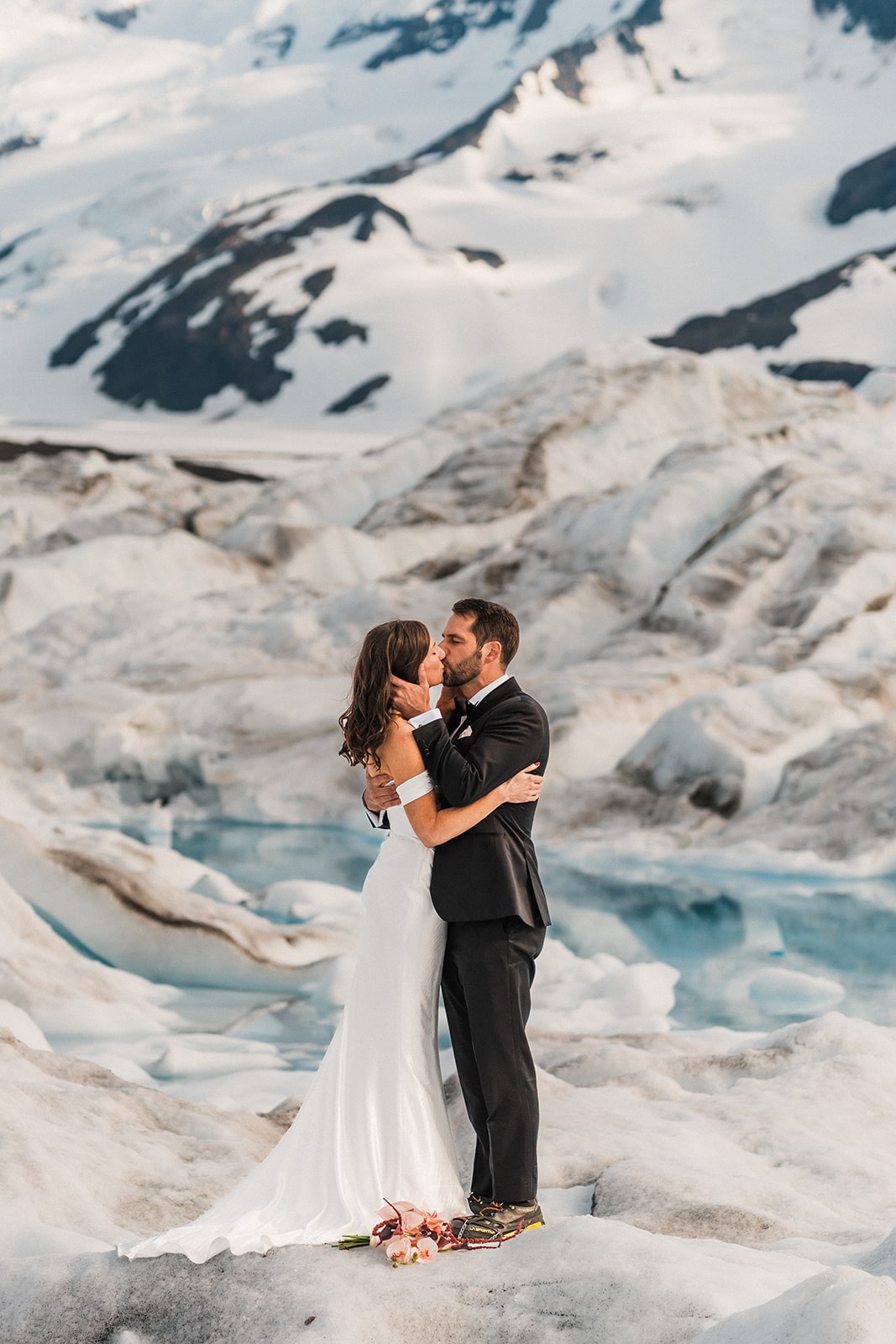 Bride and groom kiss on a snowy glacier during their Palmer, Alaska elopement.