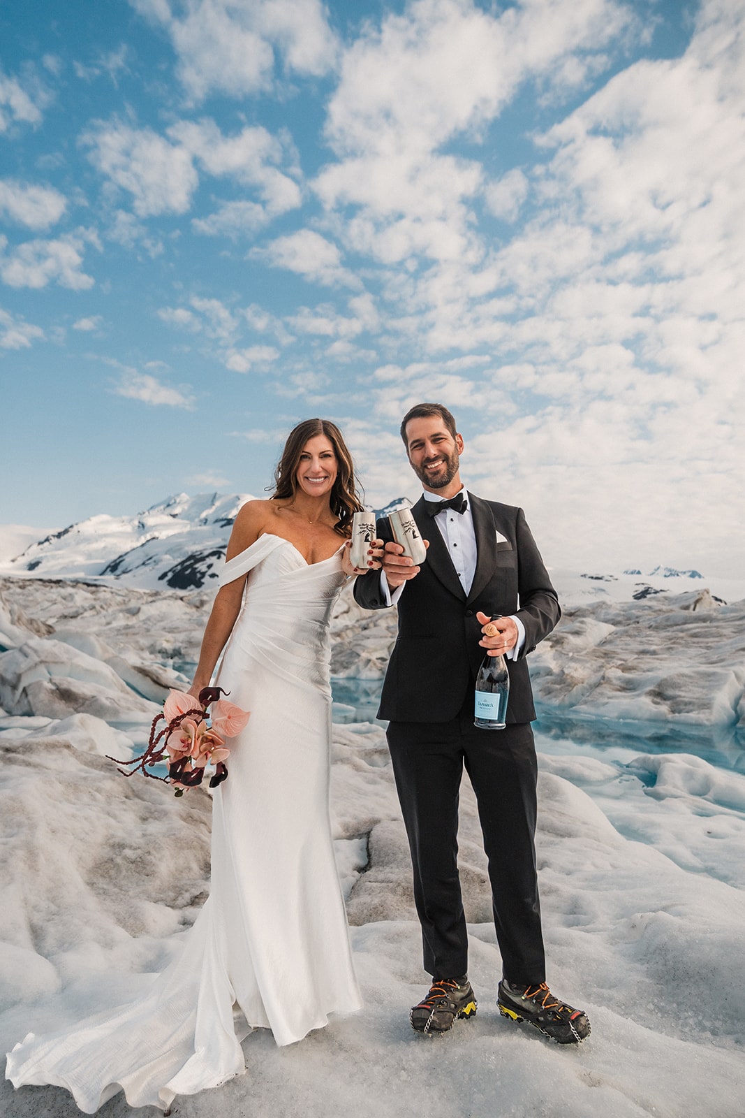 Bride and groom hold custom silver champagne flutes during their glacier elopement in Palmer, Alaska.