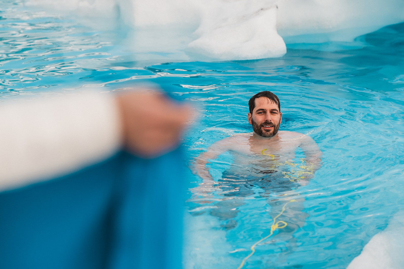 Groom plunges in glacier pool water after his multi-adventure elopement in Alaska.