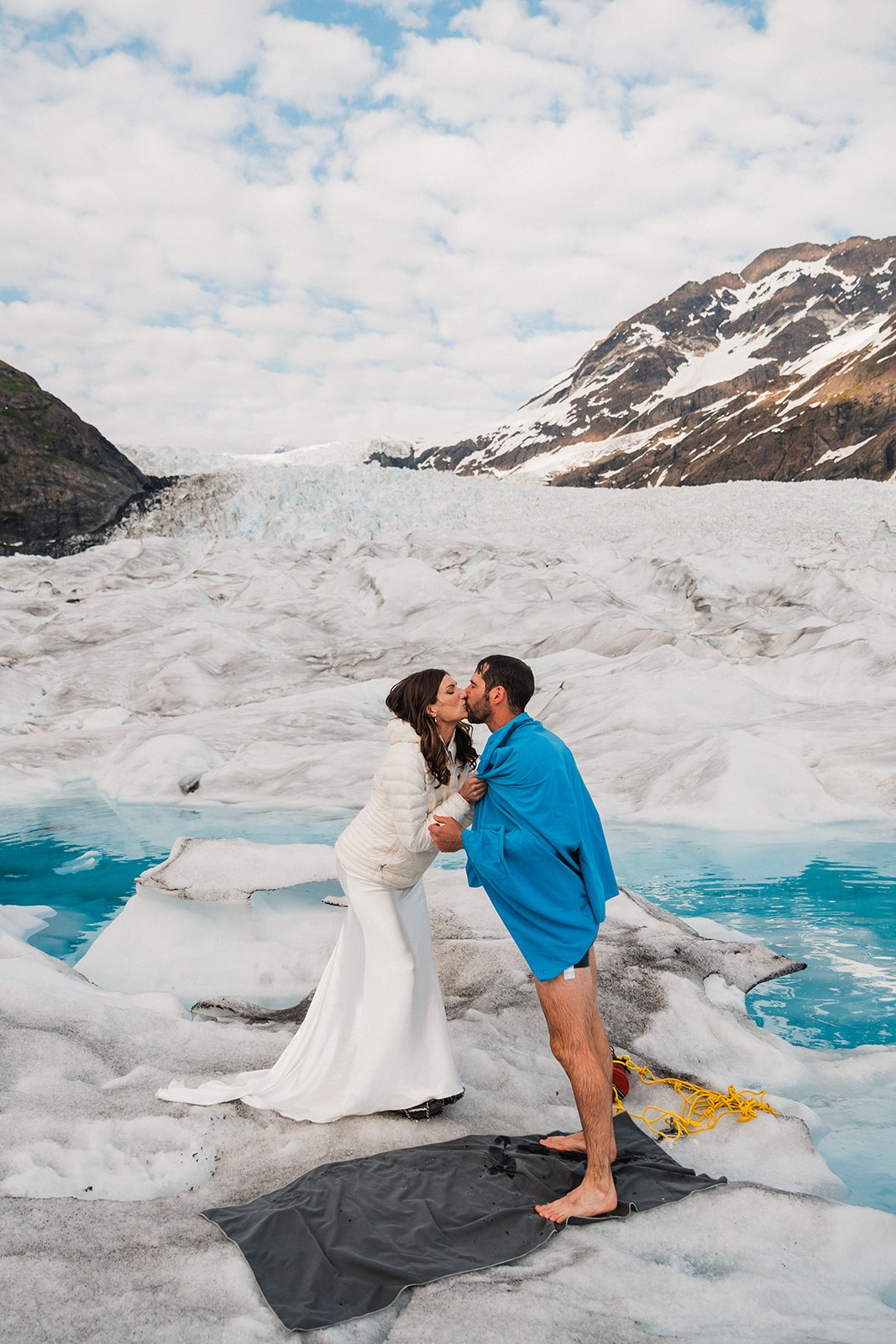 Bride and groom kiss after groom exits glacier pool.