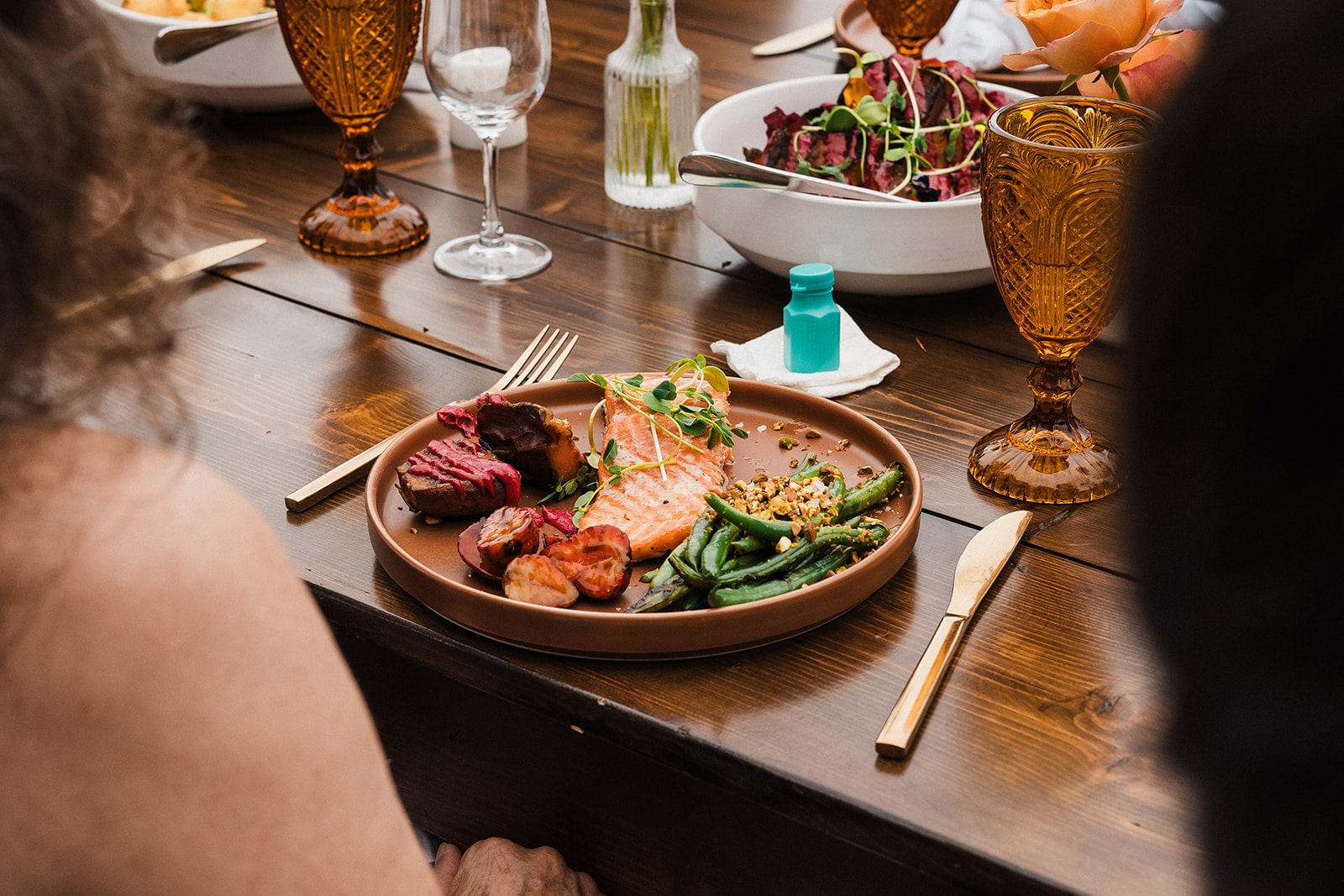 Colorful plated dinner sits on a wood table at a small wedding reception in Washington. 