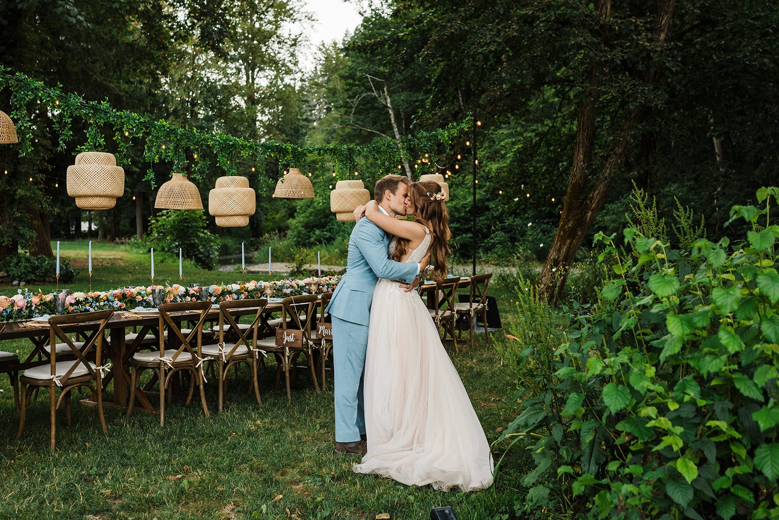 Bride and groom kiss in the backyard next to their micro wedding reception tables.