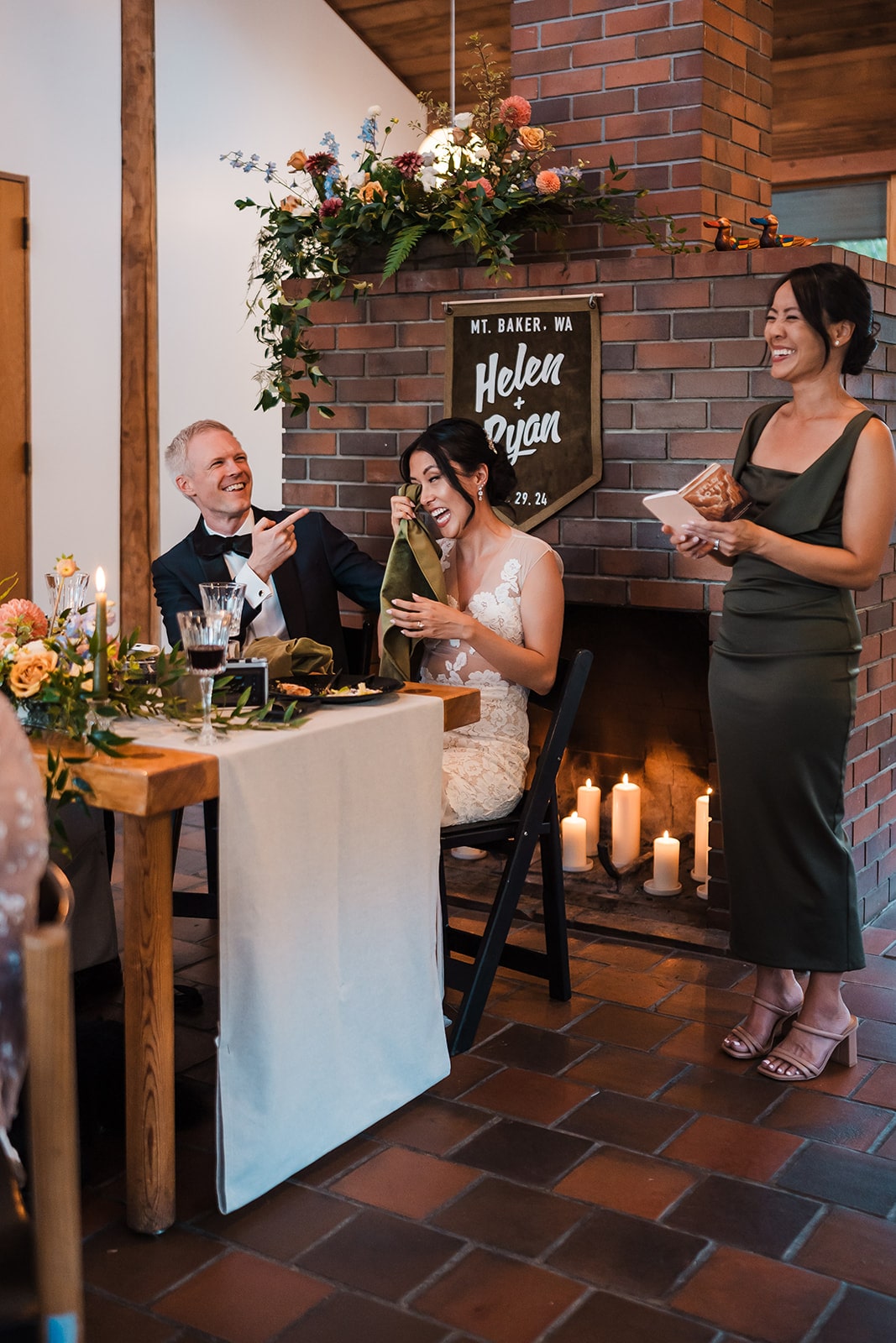 Bride and groom laugh while a guest gives a speech during their micro wedding reception. 