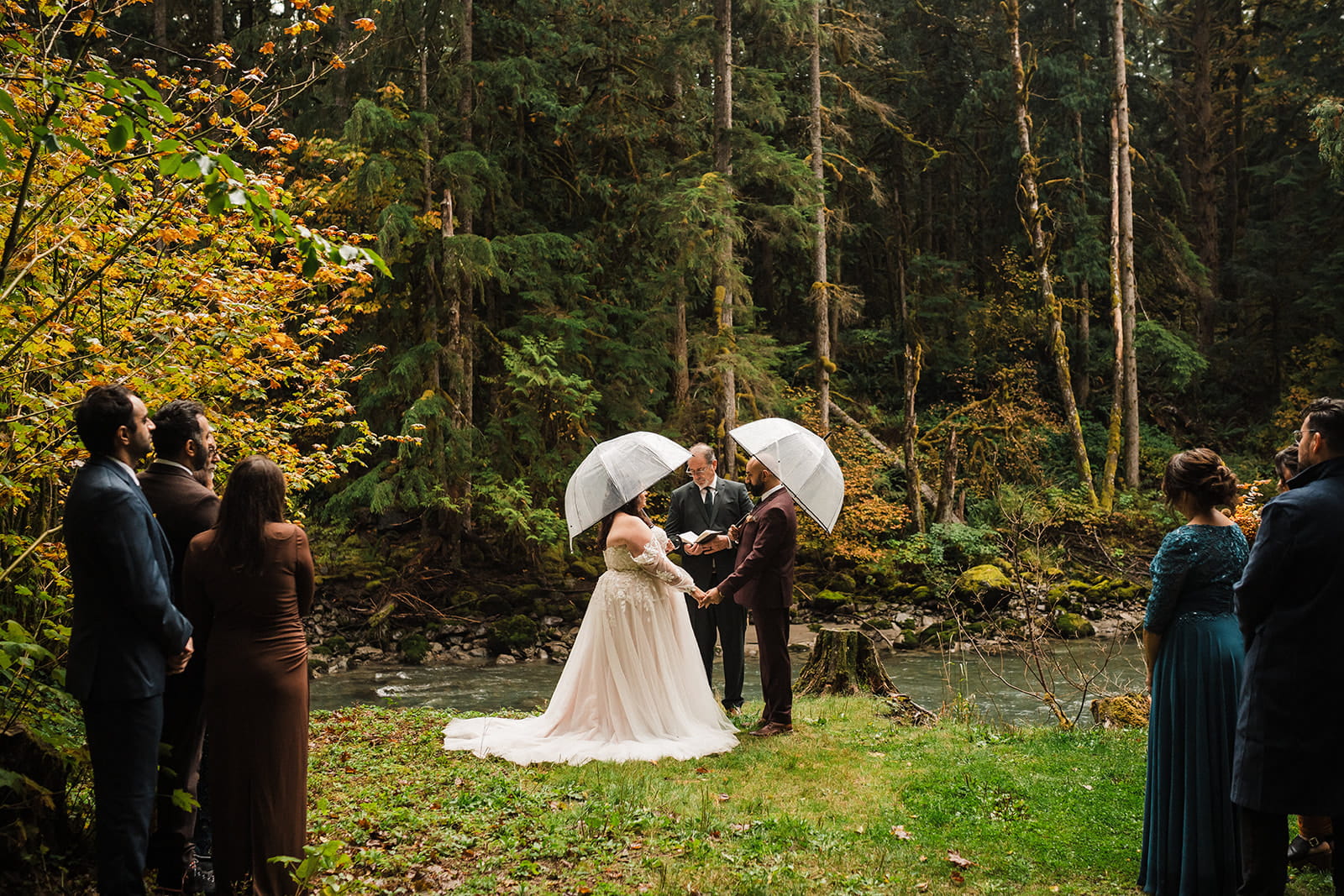 Bride and groom hold clear dome umbrellas during their rainy day wedding. 