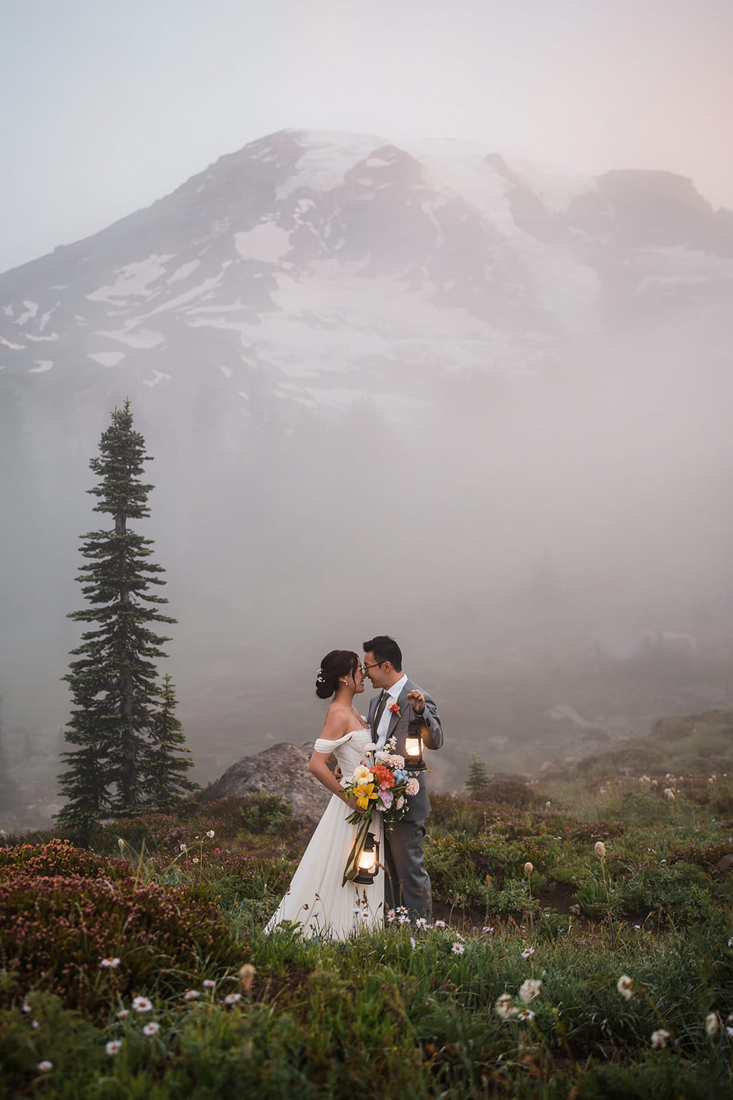 Bride and groom embrace on a foggy wildflower trail at sunrise during their Mt Rainier elopement. 