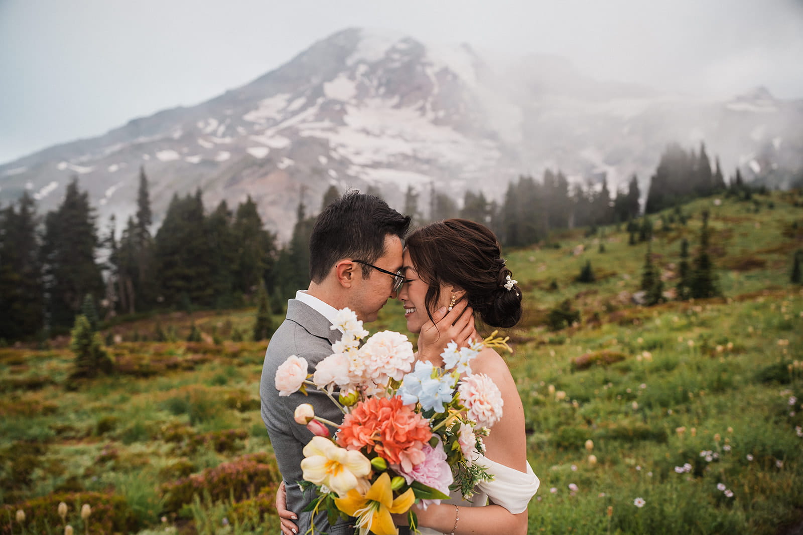 Bride and groom rest foreheads against each other during their foggy sunrise elopement at Mt Rainier National Park. 