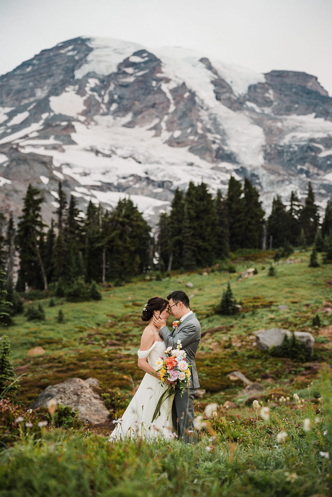 Bride and groom rest foreheads against each other during their foggy sunrise elopement at Mt Rainier National Park. 
