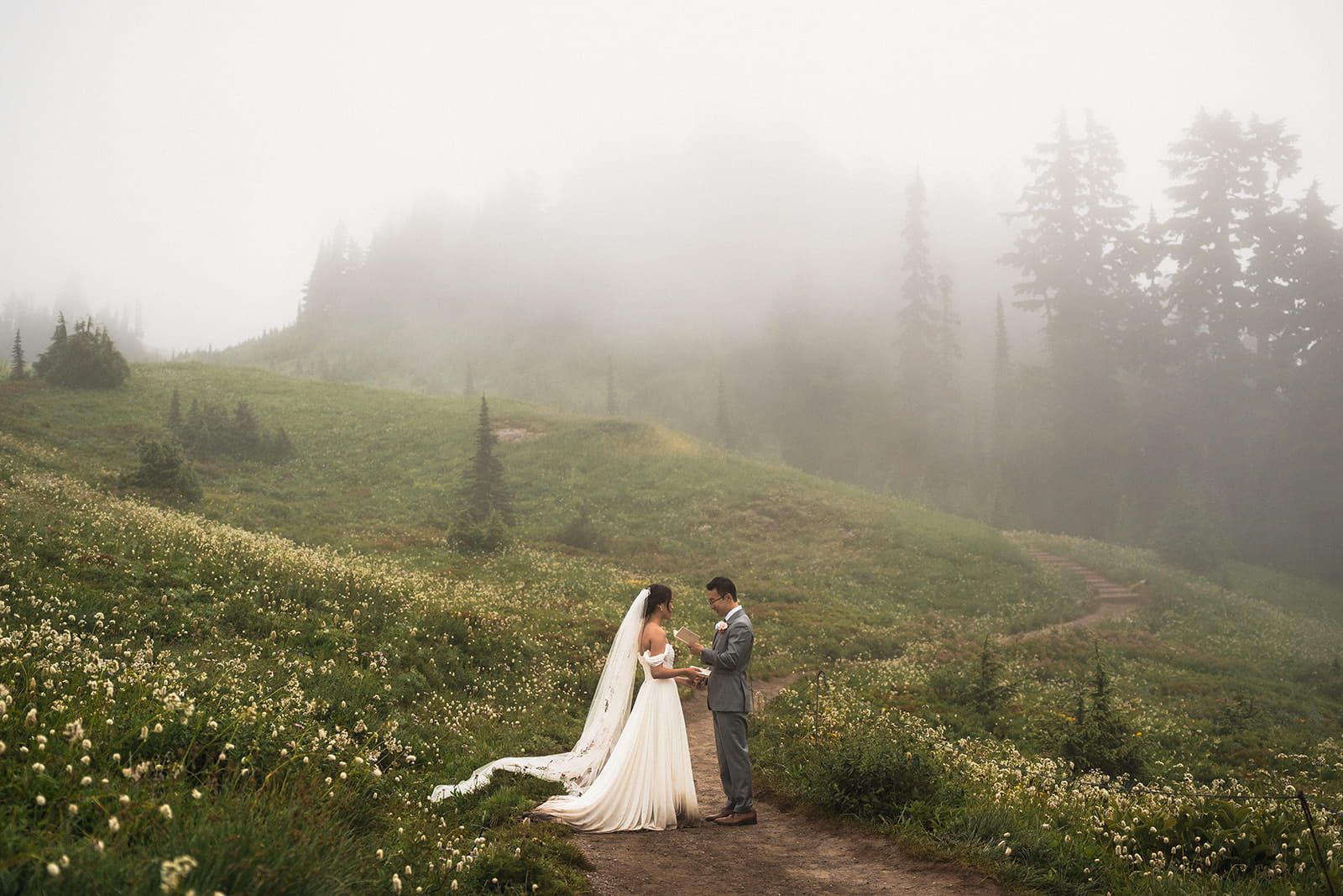 Bride and groom exchange vows on a foggy mountain trail during their wedding in Washington. 